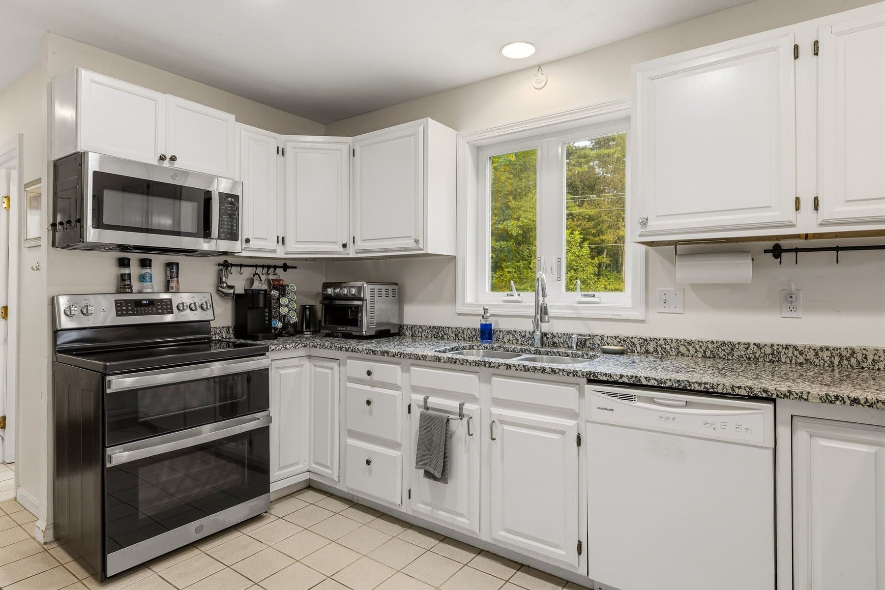 The kitchen with white cabinets, granite counters, the stainless double-oven range, and a window over the sink