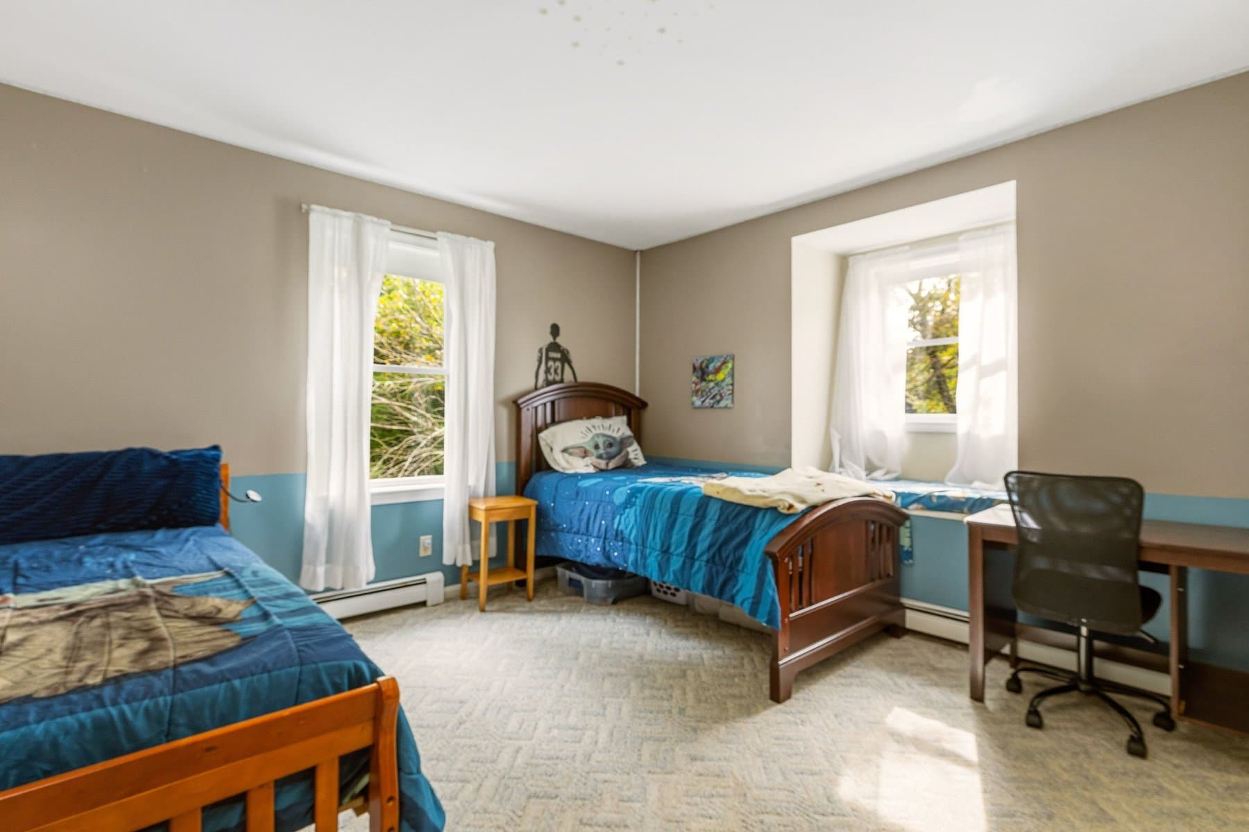 A bedroom with 2 windows, a desk, and blue two-tone walls