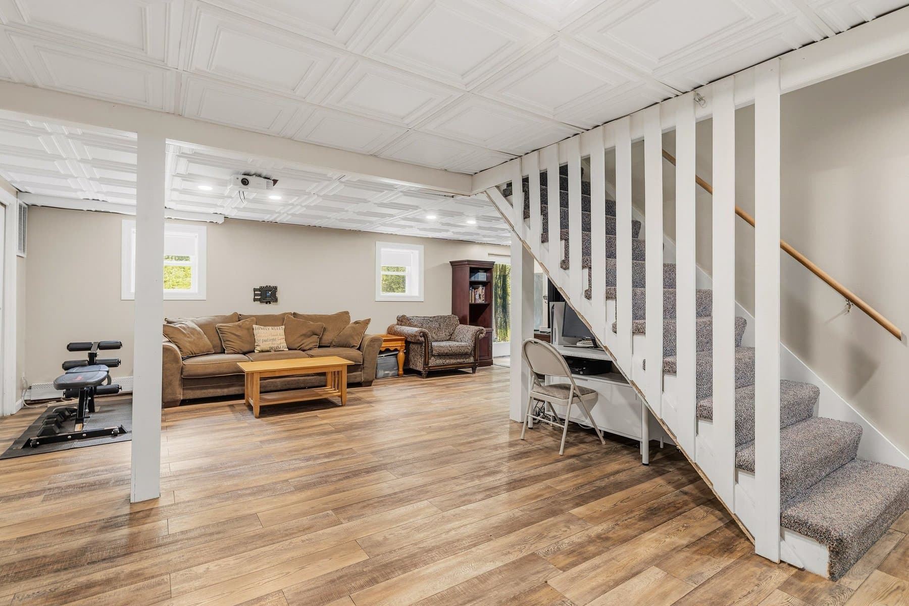 The finished walkout lower level with the stairs, a sofa, and exercise equipment