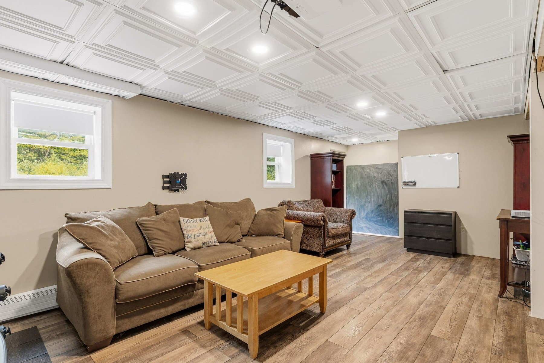 The lower level family room with a sectional, recessed lights, and windows